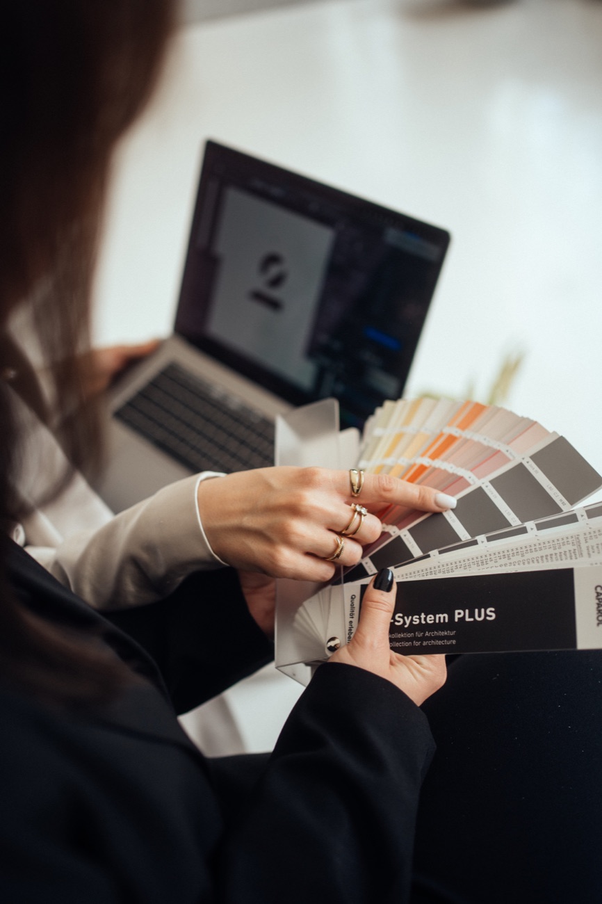 Hand mit einem Farbfächer – Auswahl von Farben und Materialien für ein Raumkonzept.